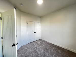 Unfurnished bedroom featuring dark colored carpet and a closet