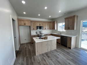 Kitchen with stainless steel appliances, a kitchen island, recessed lighting, dark wood-style flooring, and a textured ceiling