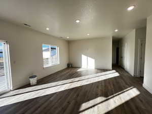 Unfurnished living room with recessed lighting, a textured ceiling, and dark wood-style floors
