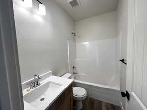 Bathroom with vanity, dark wood-type flooring, and shower / bath combination
