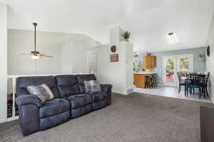 Living room featuring lofted ceiling, light colored carpet, and light tile patterned flooring