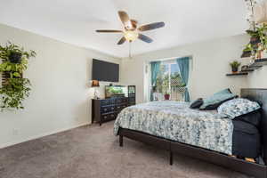 Carpeted bedroom featuring baseboards and ceiling fan