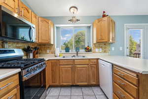 Kitchen featuring stainless steel appliances, a peninsula, light countertops, and backsplash
