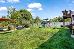 Fenced backyard with a playground and an outdoor living space