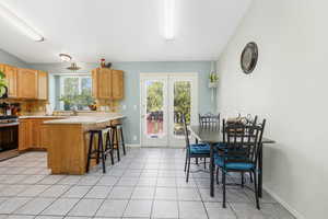 Kitchen featuring tasteful backsplash, a kitchen bar, light countertops, stainless steel stove, and light tile patterned flooring