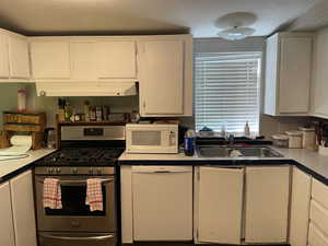 Kitchen with white appliances, white cabinets, a textured ceiling, and light countertops