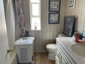 Full bathroom featuring wood finished floors, wallpapered walls, vanity, and a shower with shower curtain
