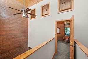 Corridor featuring brick wall, carpet flooring, and wooden ceiling