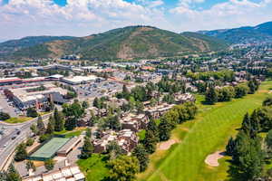 Aerial view of residential area featuring a mountain backdrop and a golf club