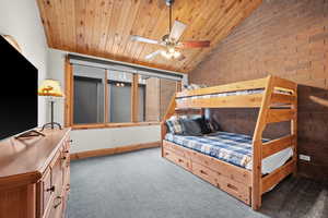 Bedroom with lofted ceiling, carpet flooring, brick wall, and wood ceiling