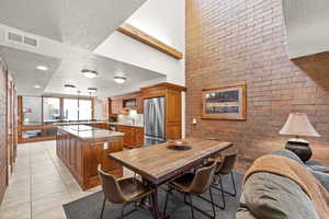 Dining area with a textured ceiling, brick wall, and light tile patterned flooring