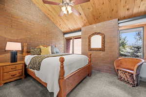 Carpeted bedroom featuring brick wall, vaulted ceiling, wood ceiling, and ceiling fan