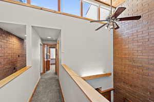 Corridor featuring brick wall, carpet, and an upstairs landing