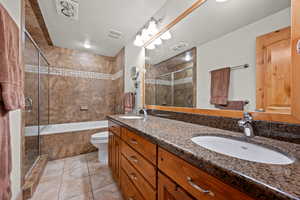 Full bathroom with double vanity, tile patterned flooring, and a textured ceiling