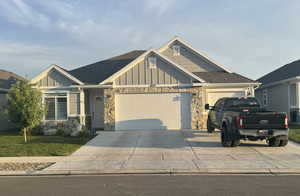 Craftsman house featuring board and batten siding, stone siding, roof with shingles, and an attached garage