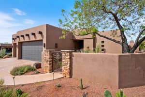 Pueblo-style house with a gate, stucco siding, a garage, and driveway