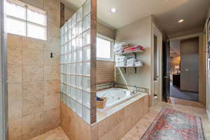 Full bathroom with a tub with jets, recessed lighting, and tiled shower