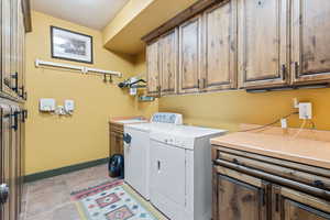 Laundry area featuring cabinet space, washing machine and clothes dryer, and light tile patterned floors