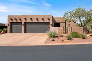 Pueblo-style house featuring stucco siding, a garage, concrete driveway, and a gate