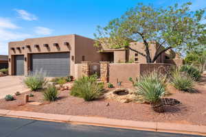 Southwest-style home with stucco siding, a fenced front yard, driveway, and a garage