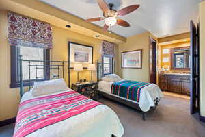 Carpeted bedroom with ceiling fan and connected bathroom