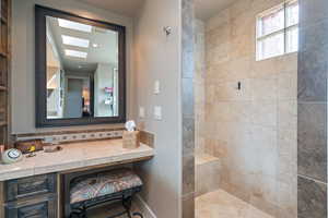 Bathroom featuring a tile shower and a skylight