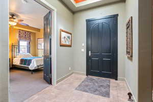 Carpeted entrance foyer with tile patterned flooring and a ceiling fan