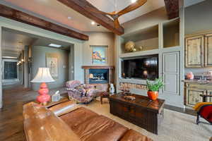 Living room featuring beam ceiling, wood finished floors, recessed lighting, a tiled fireplace, and a ceiling fan