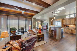 Living area featuring beamed ceiling, dark wood-style flooring, recessed lighting, a ceiling fan, and a chandelier