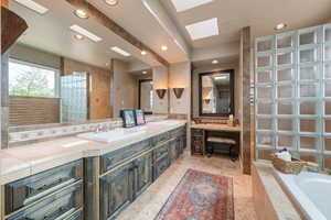 Bathroom featuring double vanity, a bath, a skylight, and recessed lighting