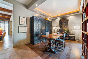 Dining room featuring dark wood-type flooring, a desk, a raised ceiling, and recessed lighting