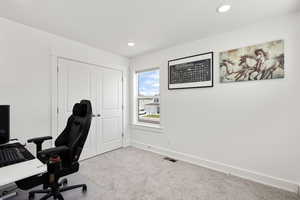 Carpeted home office or bedroom with deep closet and four windows