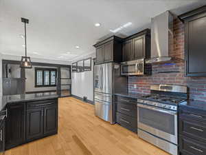 Kitchen with appliances with stainless steel finishes, island range hood, a textured ceiling, light wood-type flooring, and recessed lighting