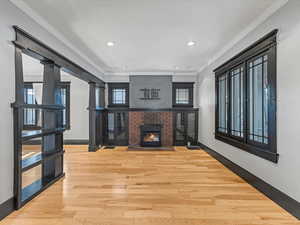 Unfurnished living room featuring crown molding, a fireplace, wood finished floors, and recessed lighting