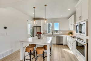 Kitchen with appliances with stainless steel finishes, white cabinets, light wood-type flooring, and recessed lighting