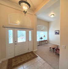 Entrance foyer with light colored carpet and light tile patterned floors