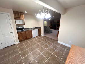 Kitchen featuring a chandelier, dark countertops, dark tile patterned flooring, stainless steel microwave, and recessed lighting