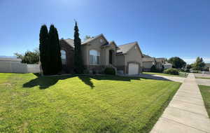 View of front facade featuring stucco siding, driveway, a garage, and brick siding