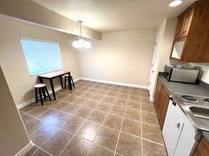 Tiled dining room with baseboards and a chandelier