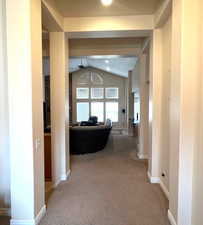 Hall with vaulted ceiling and carpet floors leading into the real great room