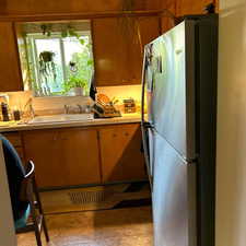 Kitchen featuring freestanding refrigerator and a sink