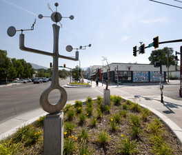 View of asphalt road with traffic lights, sidewalks, and street lights