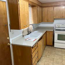 Kitchen featuring white range with electric cooktop, light countertops, and brown cabinets