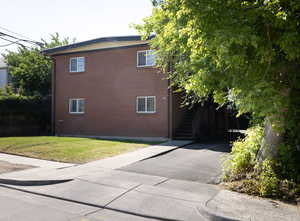 View of property exterior featuring brick siding and a lawn