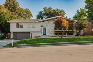 Raised ranch with a front lawn, concrete driveway, a garage, and brick siding