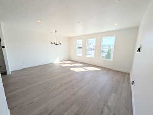 Unfurnished living room with light wood-type flooring, a chandelier, and recessed lighting