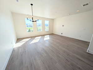 Unfurnished dining area featuring a chandelier, wood finished floors, and recessed lighting