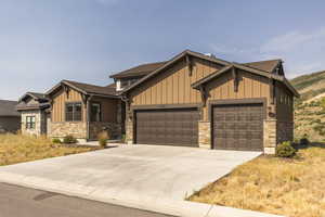 Craftsman-style home with board and batten siding, an attached garage, concrete driveway, and roof with shingles