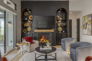 Living area featuring built in features, a lit fireplace, and wood finished floors