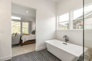 Ensuite bathroom featuring plenty of natural light, a soaking tub, and recessed lighting